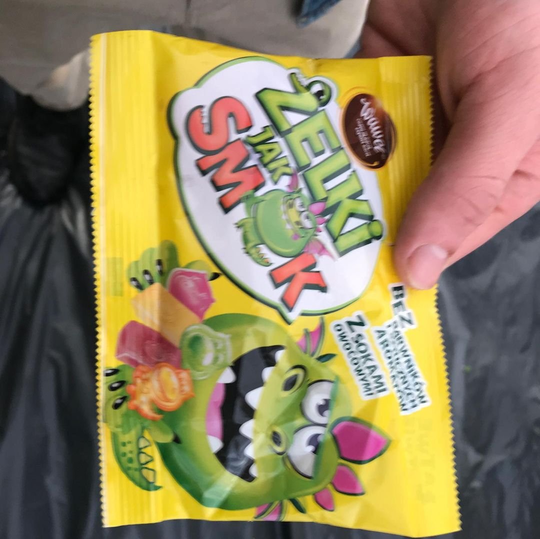 Colorful package of EZAKI's Green Snakes candy with a cartoon green snake character on the front, held by a person's hand.
