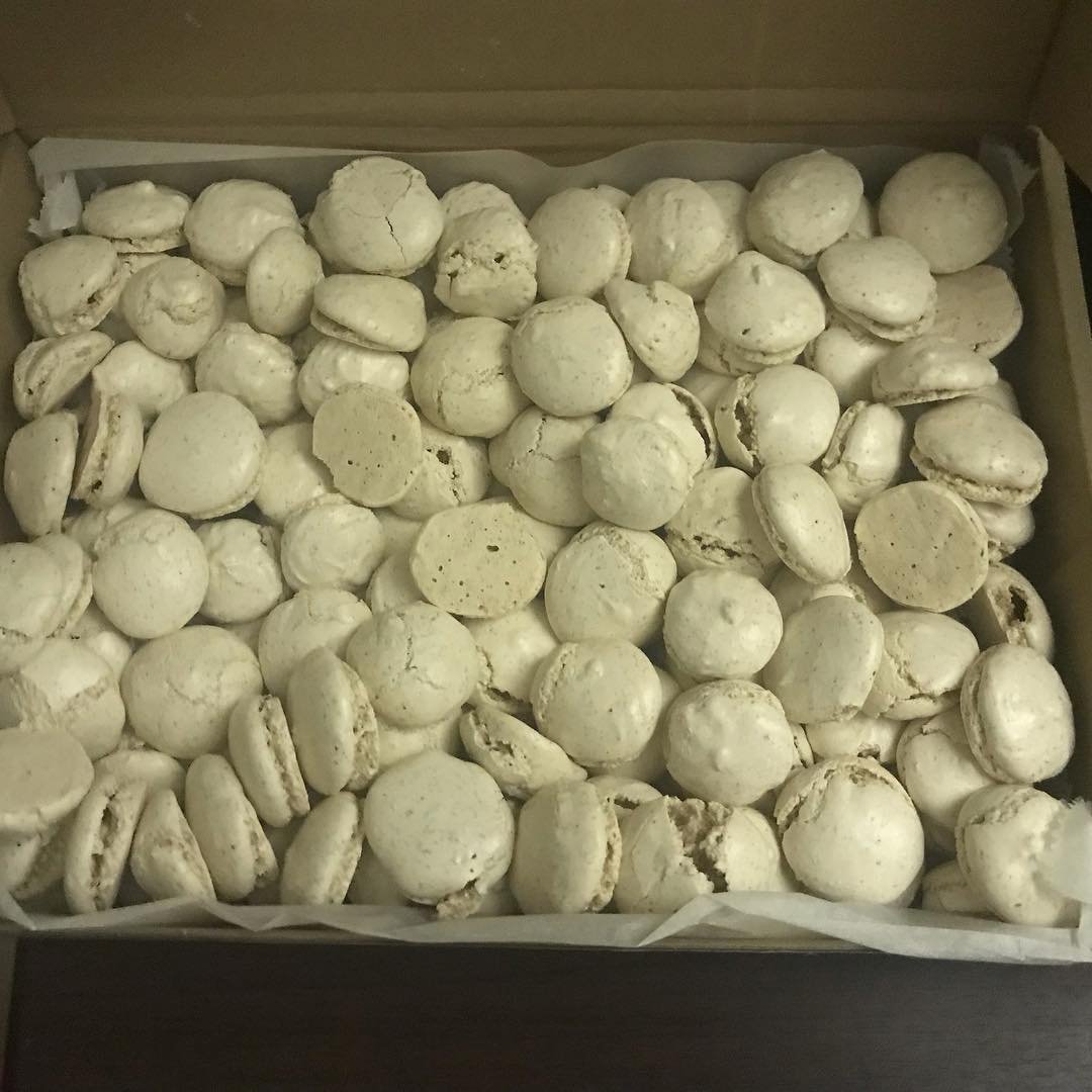 A box filled with numerous white macaron cookies.