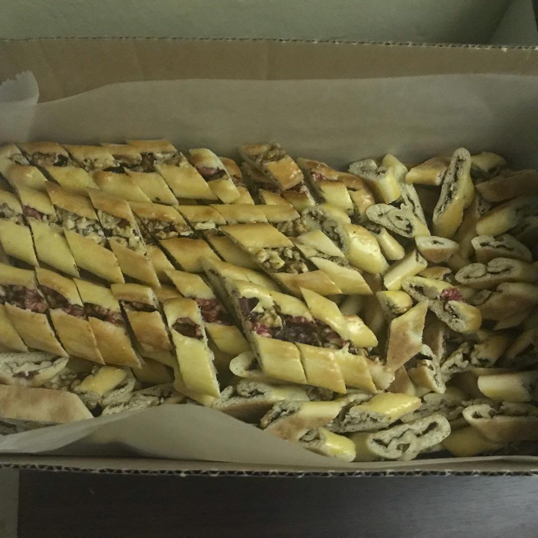 Assorted broken bakery items, including pieces of bread with chocolate and possibly some pastries, in a cardboard box lined with parchment paper.