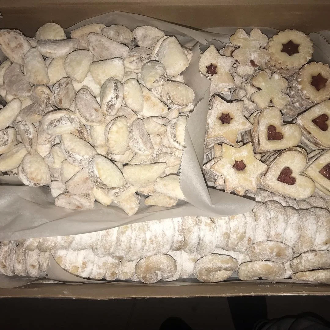 Assorted Christmas cookies, including star-shaped, heart-shaped, and crescent-shaped, decorated with icing and powdered sugar.