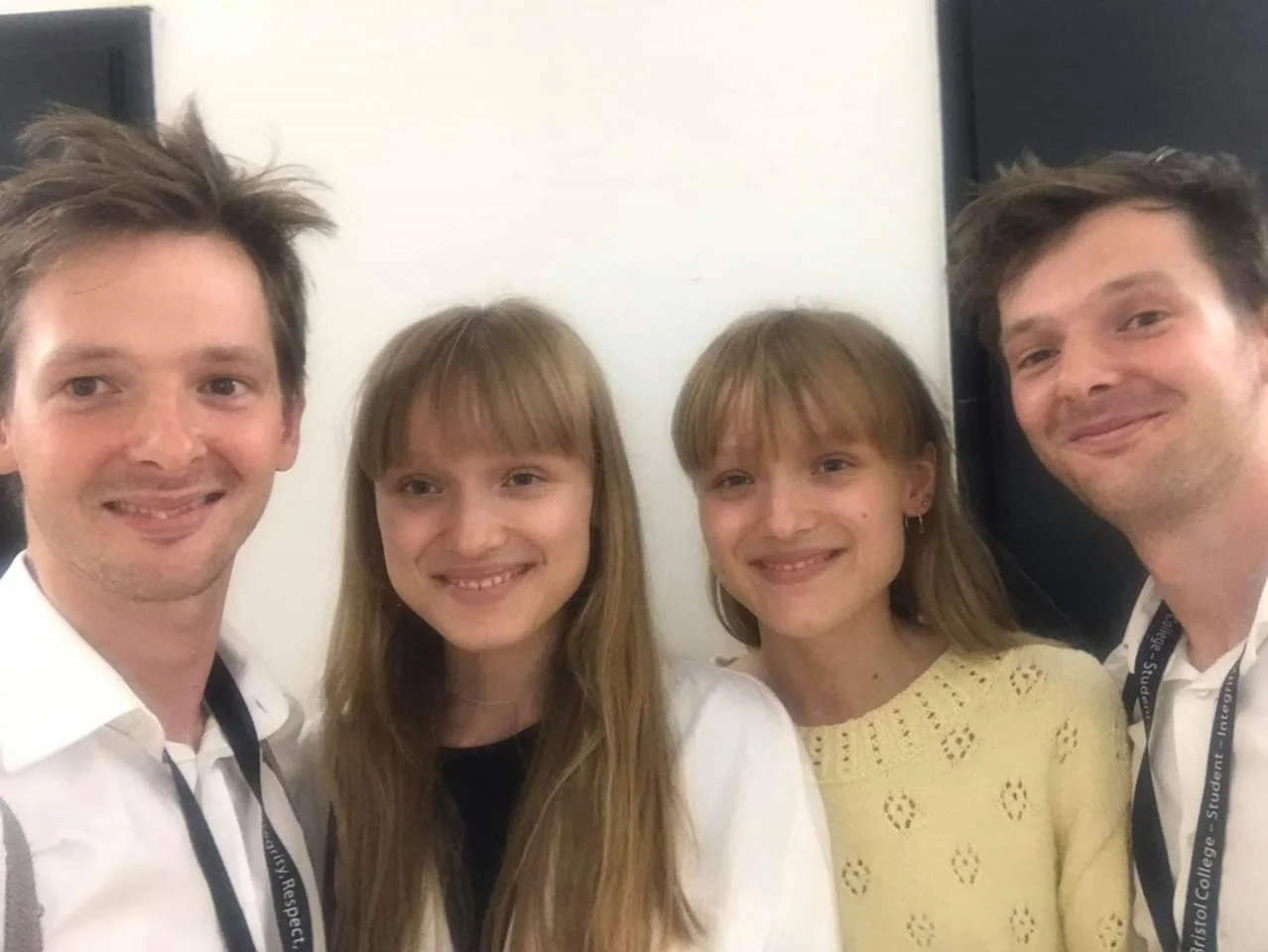 Four people smiling for a photo, two men and two women, in an indoor setting.