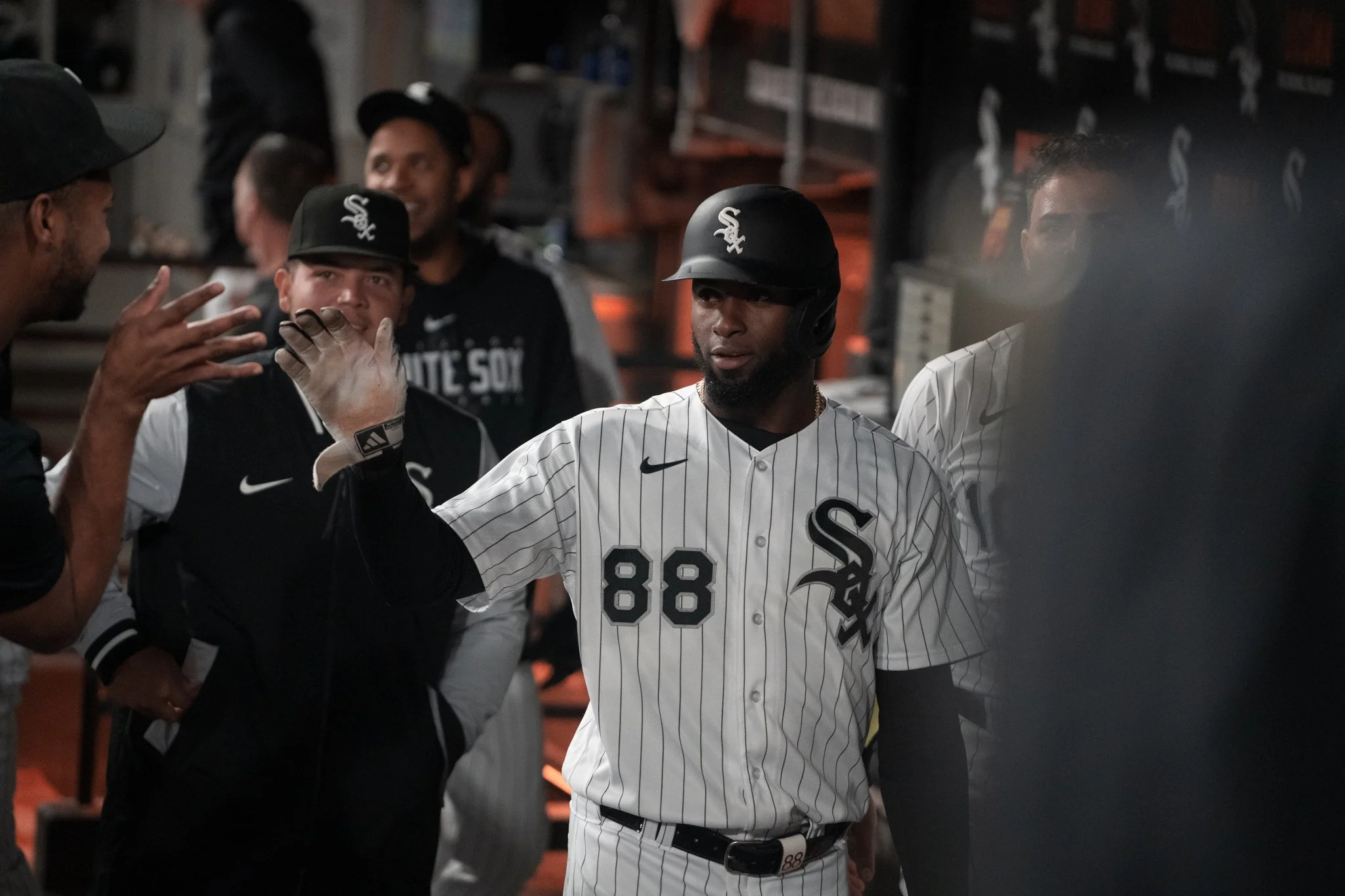 Baseball players in the locker room, with one player in a Chicago White Sox uniform giving a high five to a teammate.