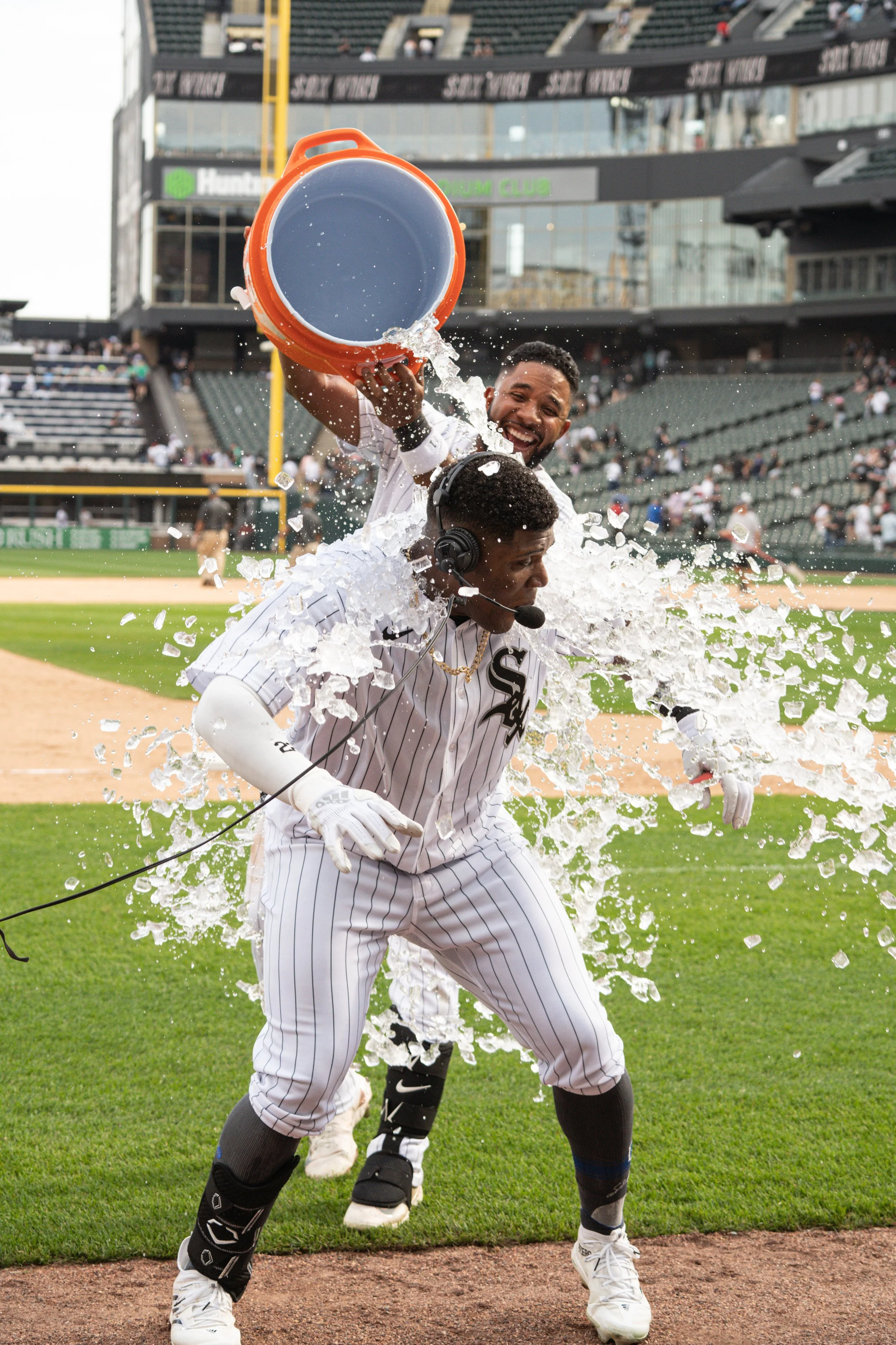Baseball players celebrating on the field, one pouring a bucket of water over the other's head during a game.