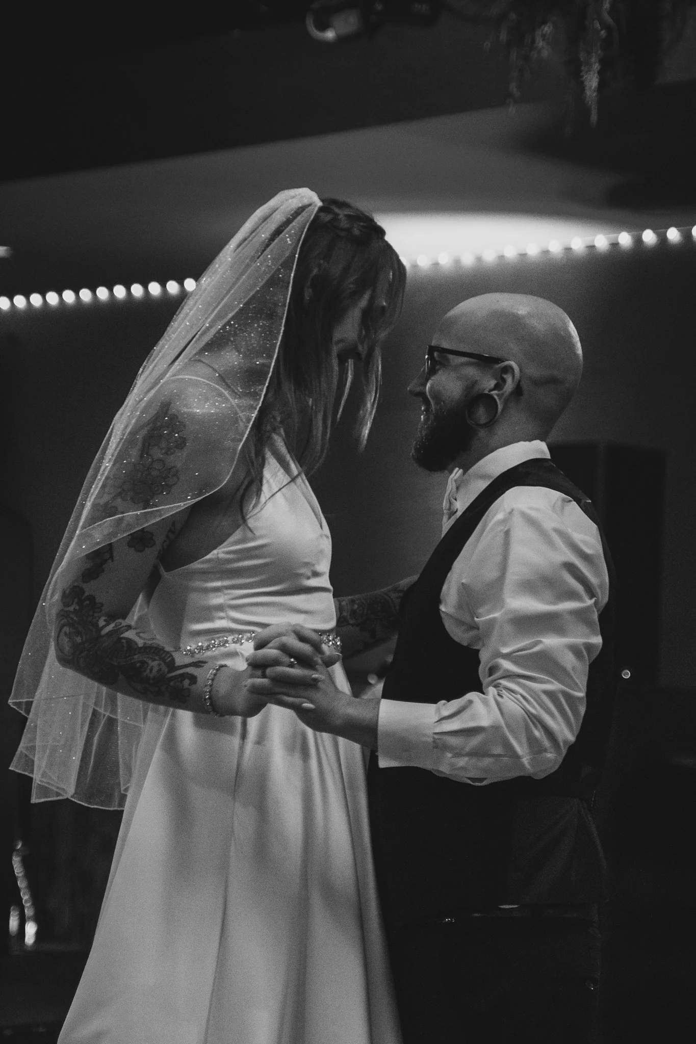 A bride and groom share a dance at their wedding reception in black and white.