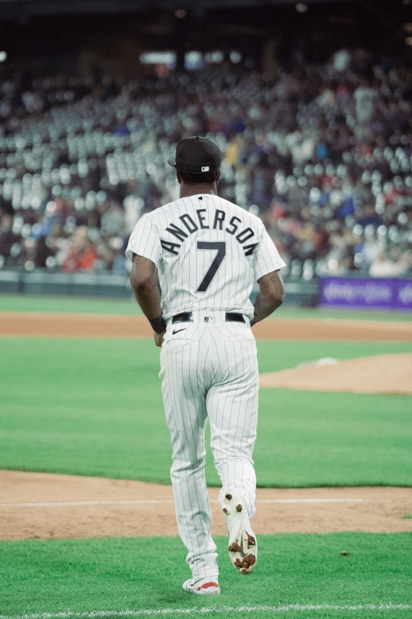 A baseball player wearing a white pinstriped uniform with the name 'Anderson' and number 7 on the back, walking on a baseball field.