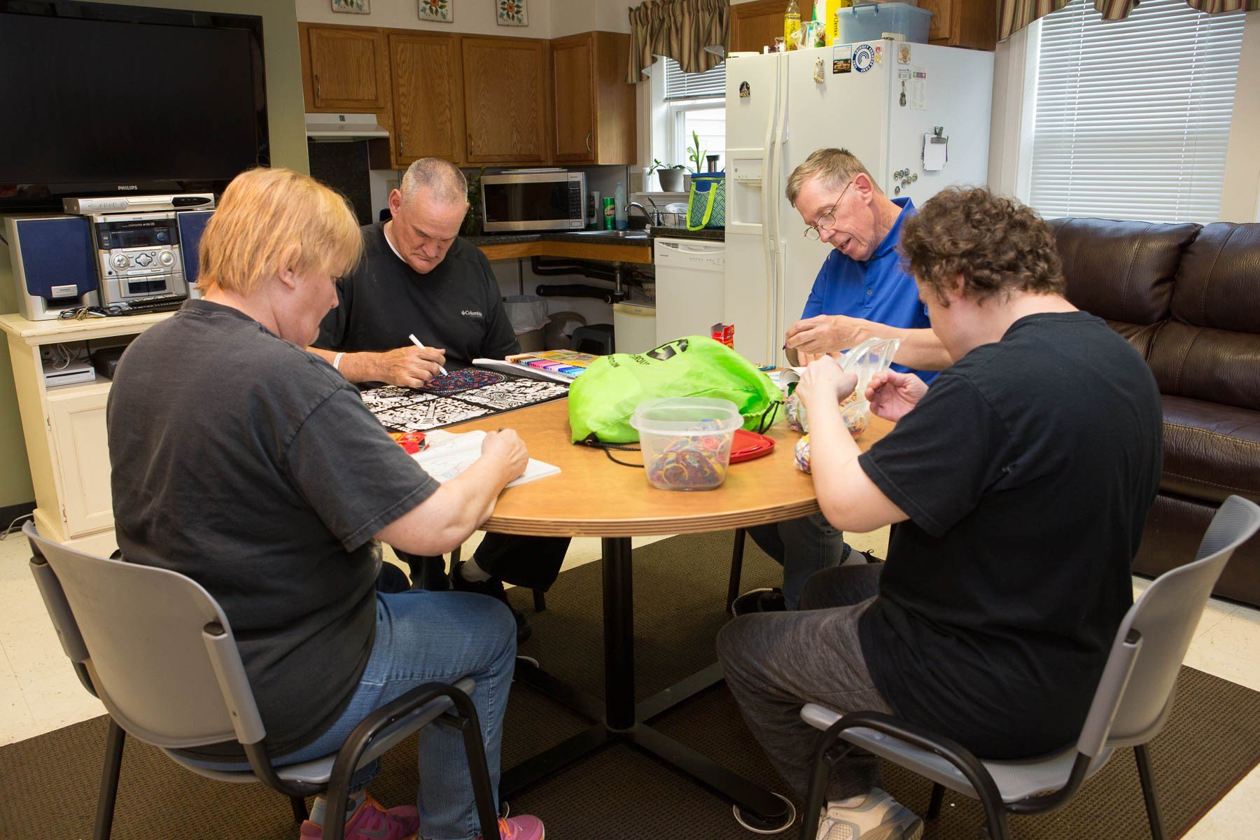A family of four sits around a kitchen table snacking and playing games