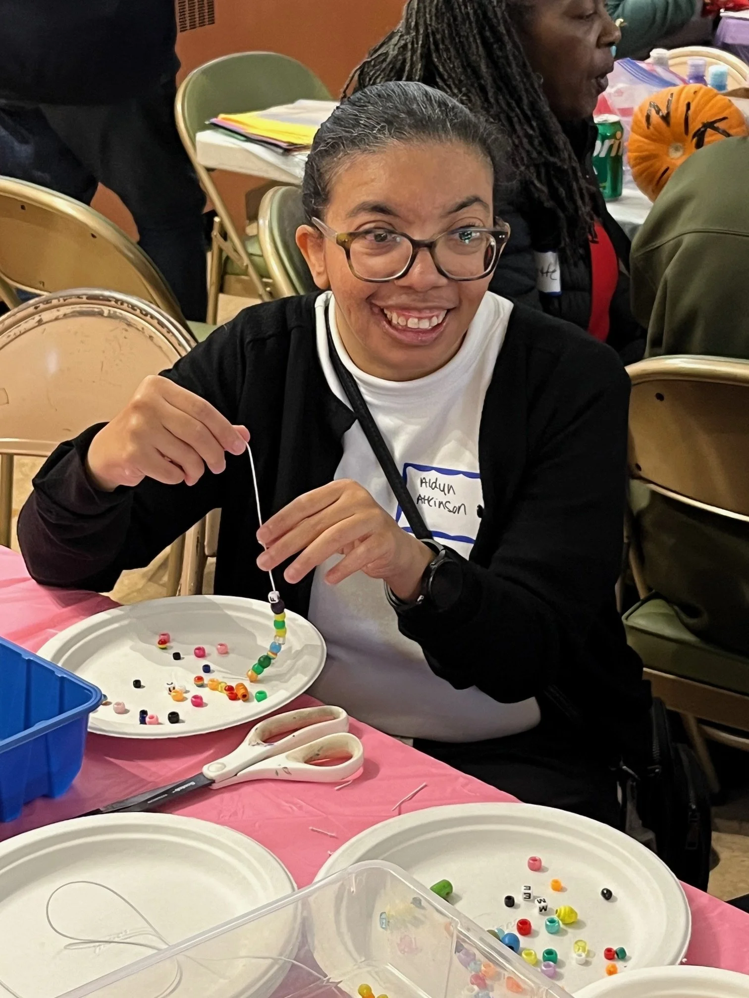 Aldyn, smiling and threading beads onto a string at the Fall Festival.