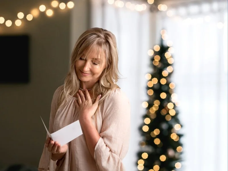 Woman reading letter near Christmas tree