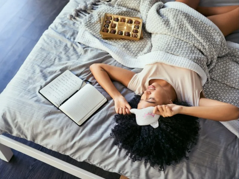 Relaxing in bed with chocolates, notebook