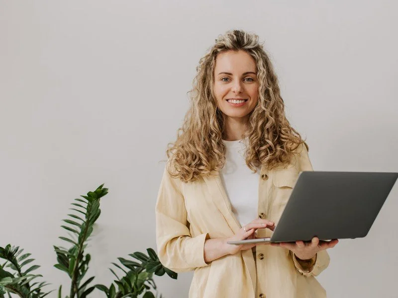 Smiling professional holding a laptop.