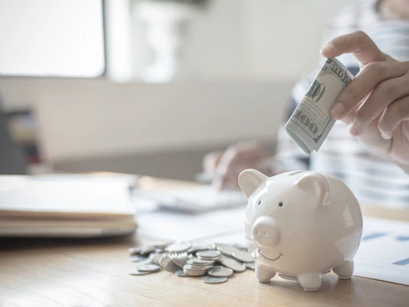 Piggy bank with coins on desk.
