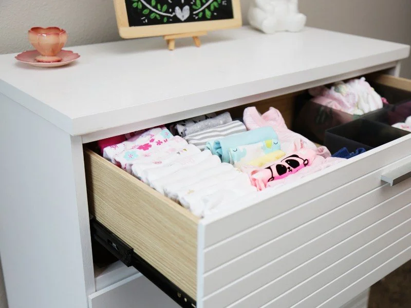 Organized drawer of baby clothes.