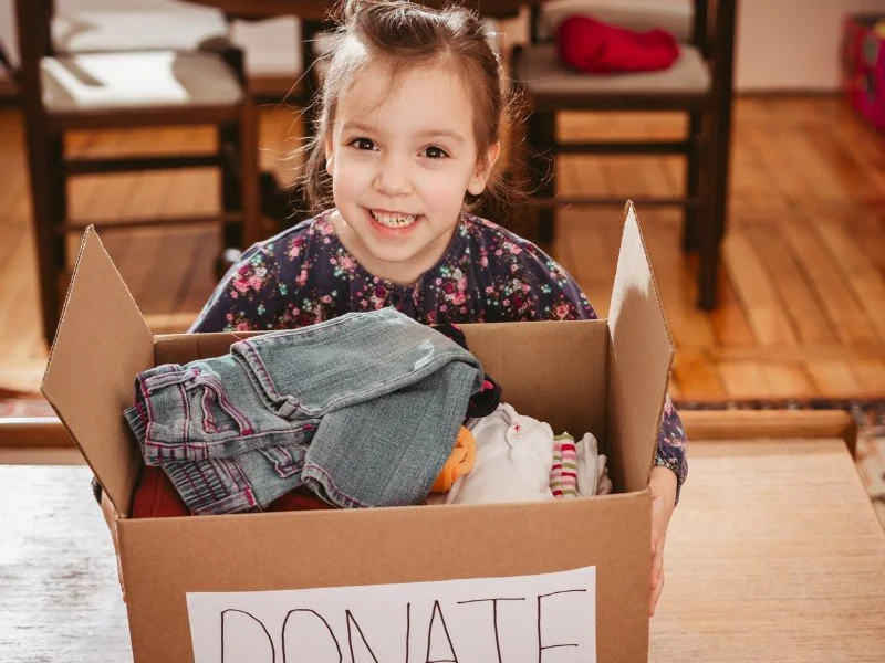 Smiling girl donating clothes.