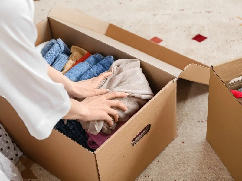 Packing clothes into a cardboard box.