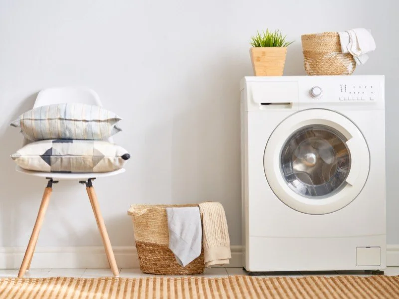 Laundry setup with a washing machine and folded towels. (Copy) (Copy)