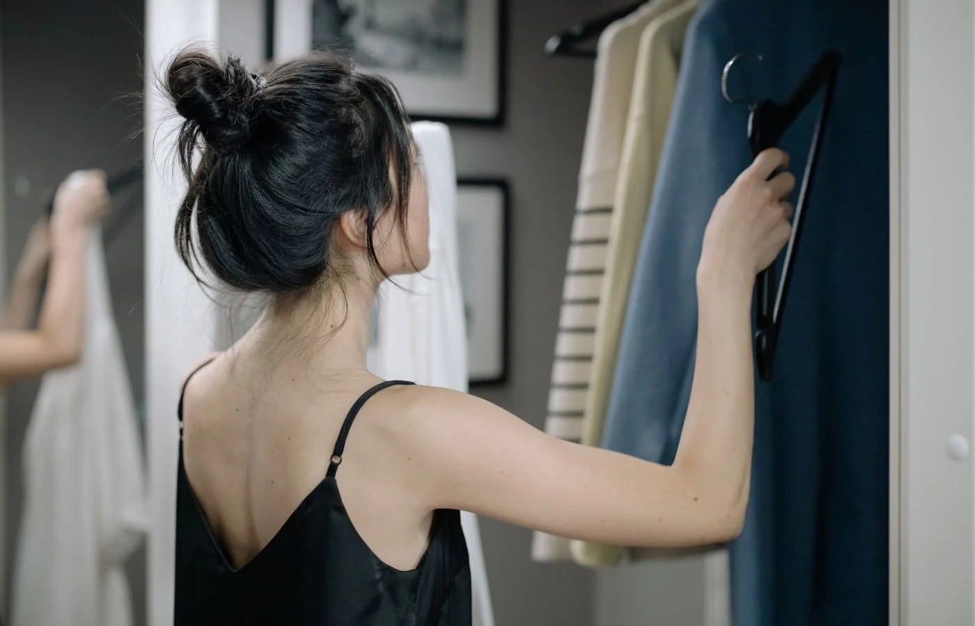 ow to curate a wardrobe Woman choosing clothes from wardrobe.