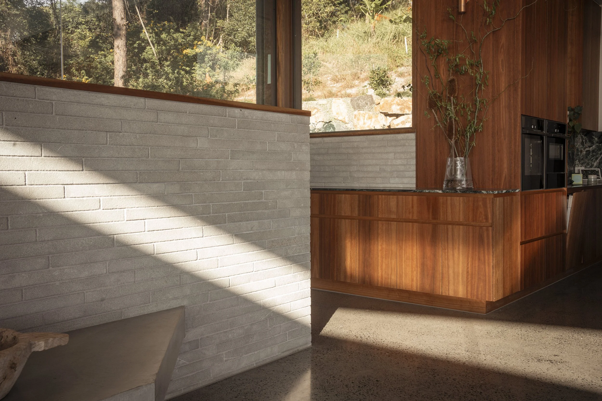 Interior view of a modern home showing a white brick half-wall, a wood-paneled wall with built-in appliances, Cape House, Suffolk Park – architectural photography