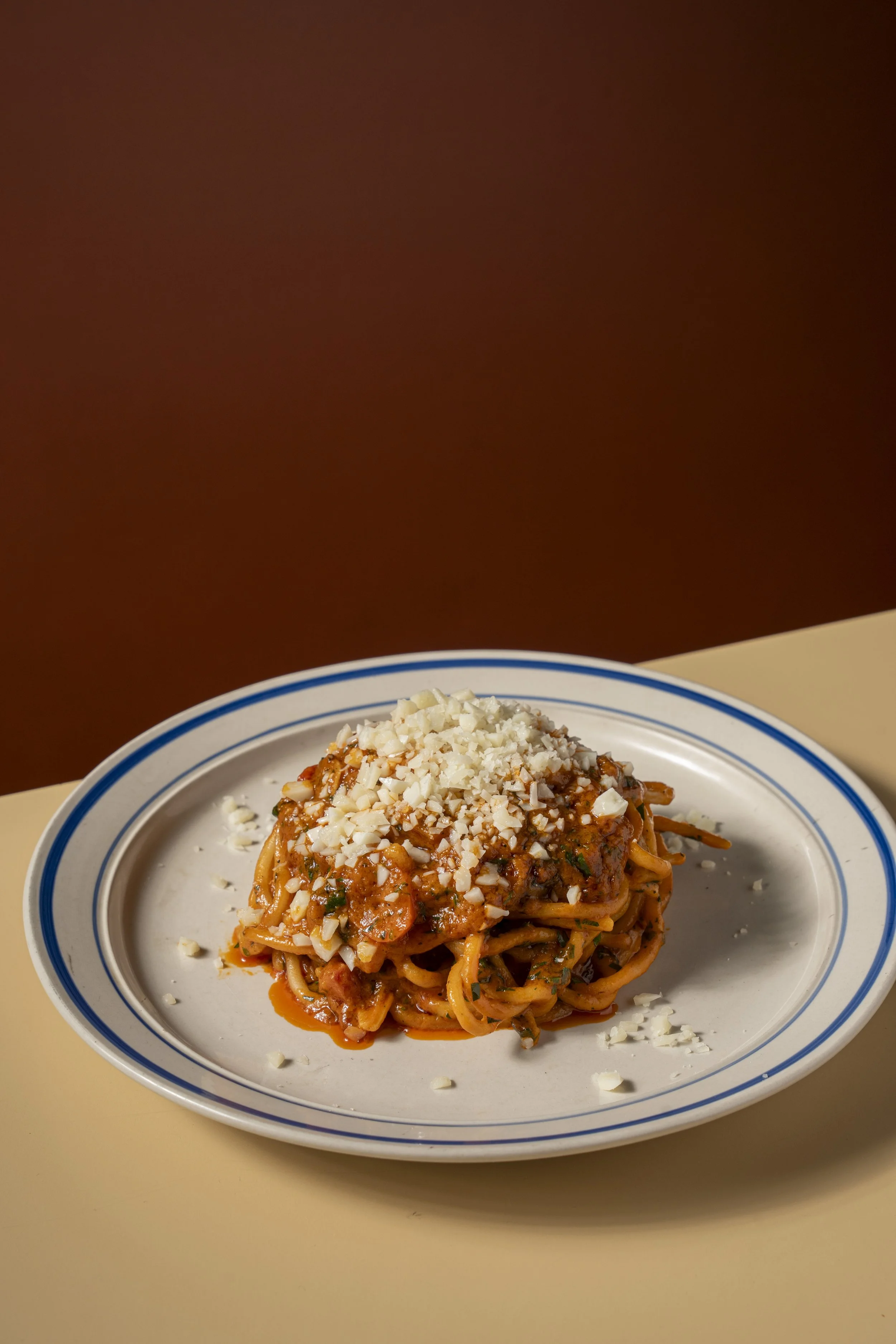 Plate of spaghetti with tomato sauce and cheese on a white plate with a blue rim. Gold Coast | Byron Bay Food Photography by Joey Bailey
