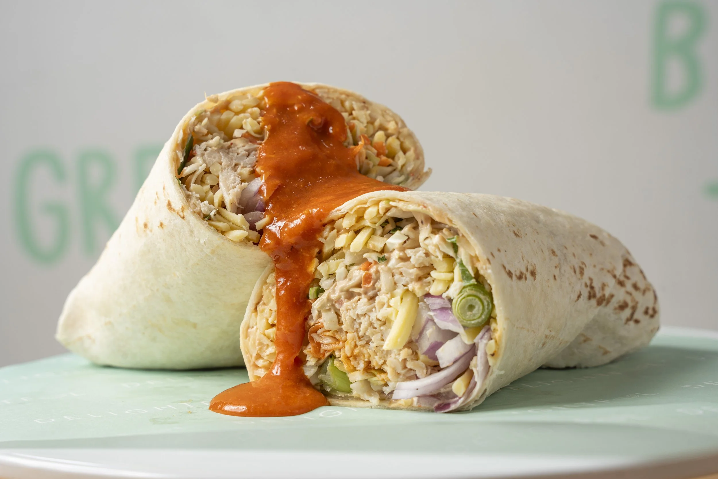 Cut chicken wrap with shredded chicken, lettuce, onions, cheese, and hot sauce inside a flour tortilla. Gold coast food photography by Joey Bailey