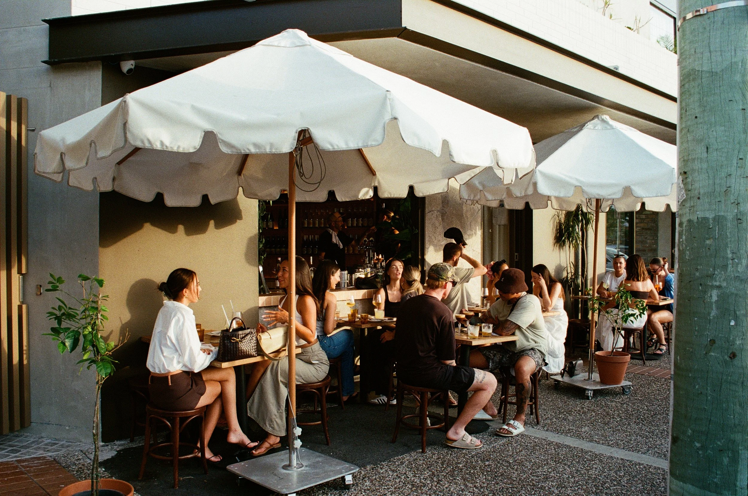 People dining outside at a restaurant with white umbrellas, Gold Coast restaurant photography