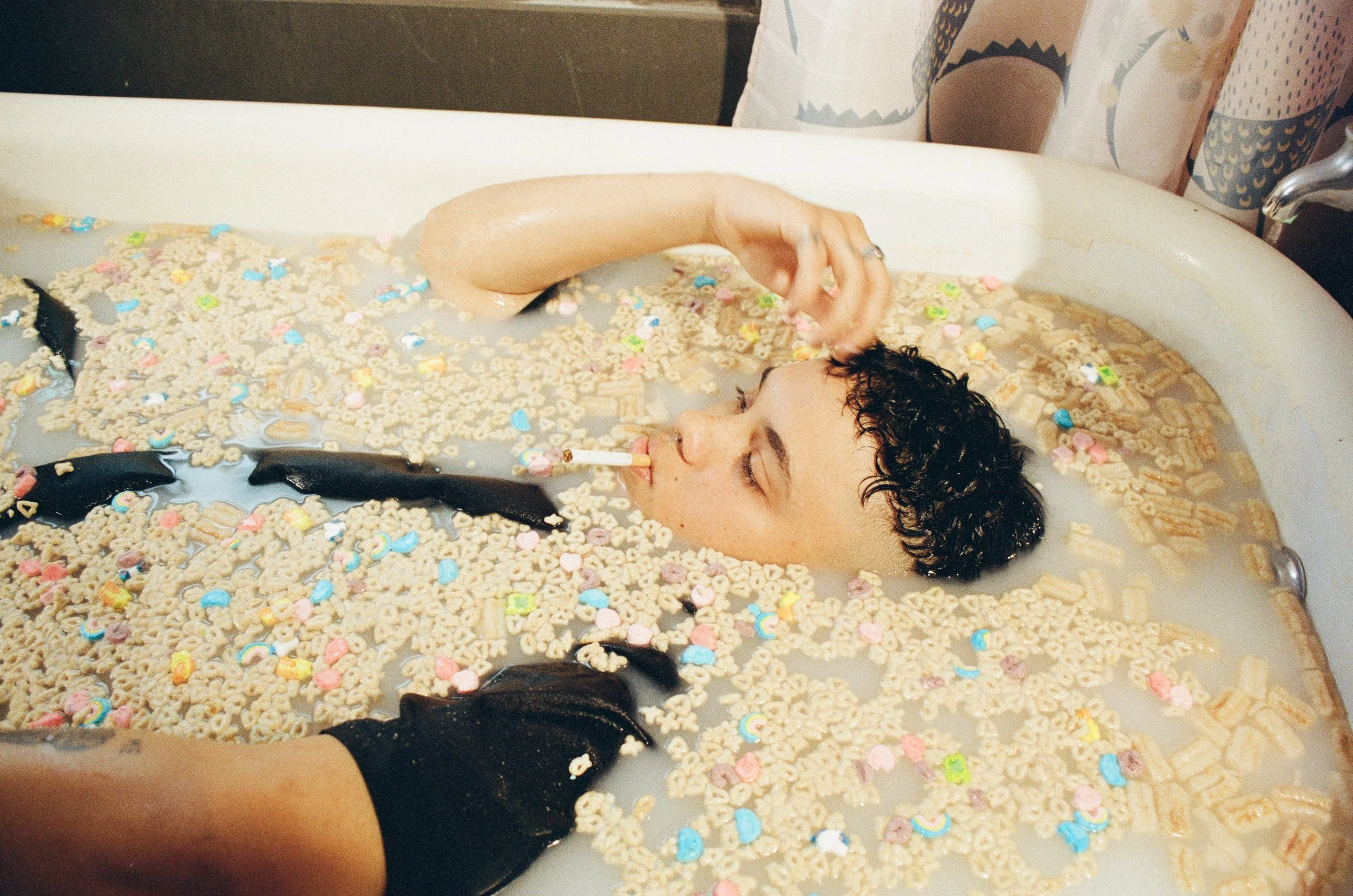 Person in a bathtub with cereal and milk, smoking a cigarette