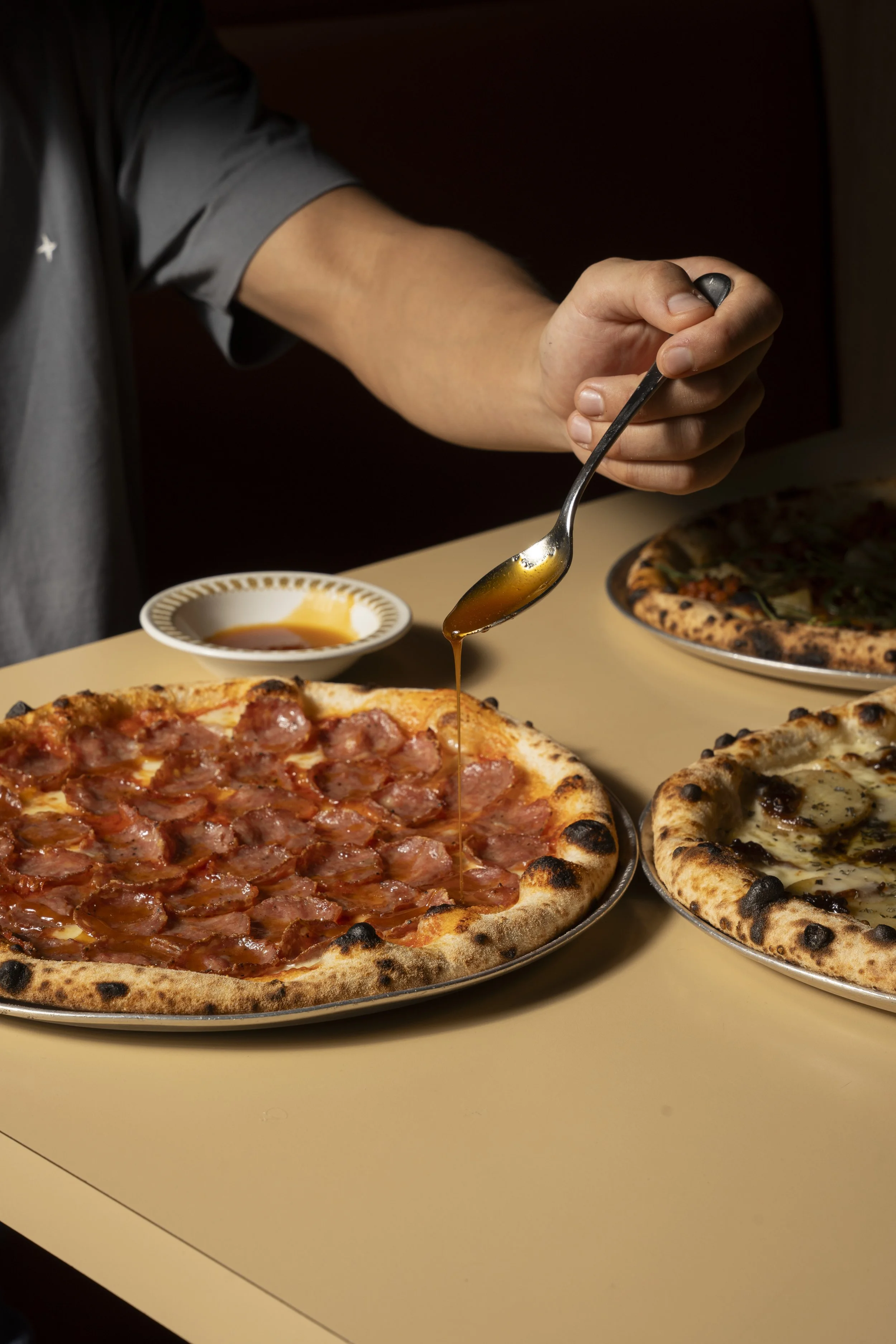Person drizzling honey on a pepperoni pizza.Gold Coast | Byron Bay Food Photography by Joey Bailey