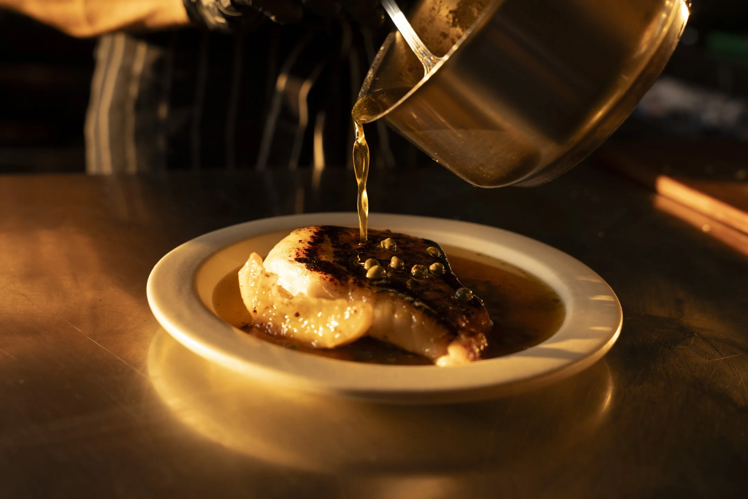 A plate with a grilled piece of fish topped with a dollop of mashed potatoes or creamy sauce, garnished with small round toppings, Gold Coast Food Photography by Joey Bailey