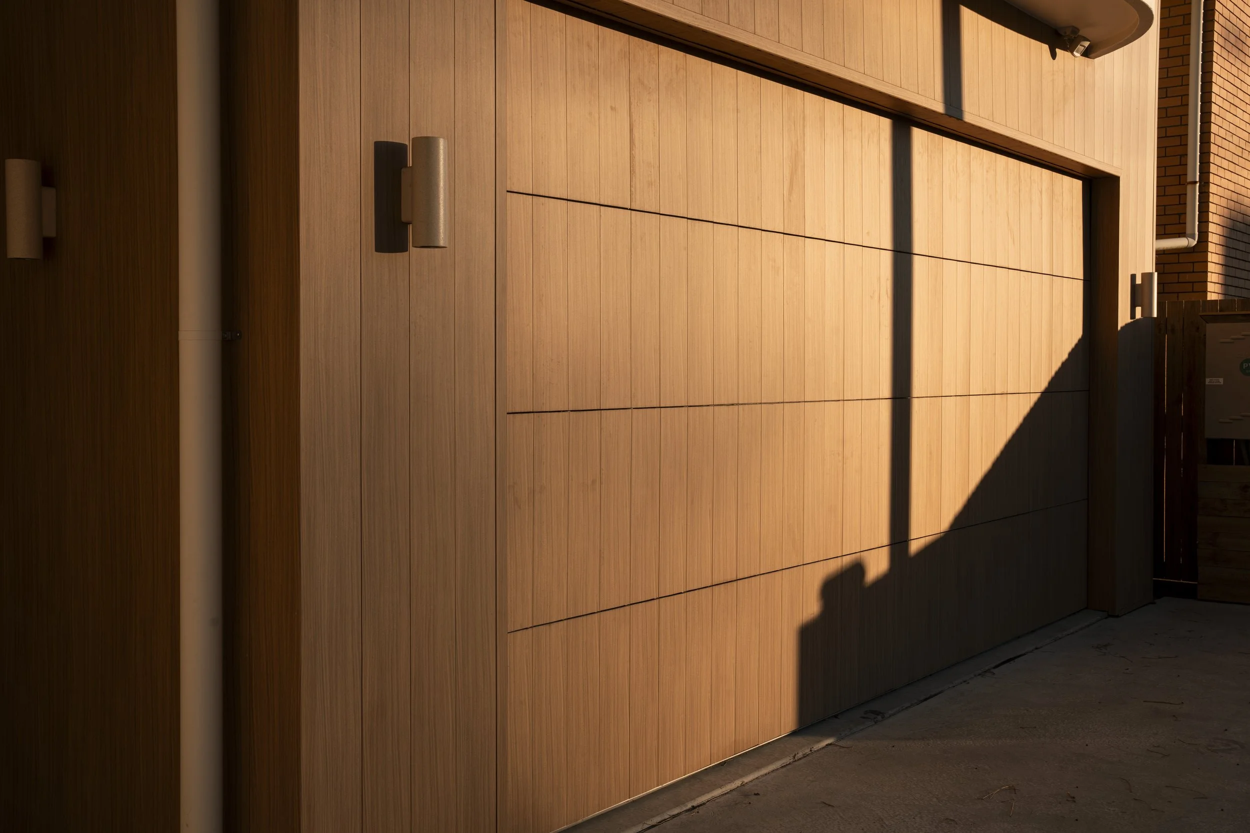 Wooden garage door with sunlight and shadows, part of a building exterior. Architectural photography by Joey Bailey, Gold Coast