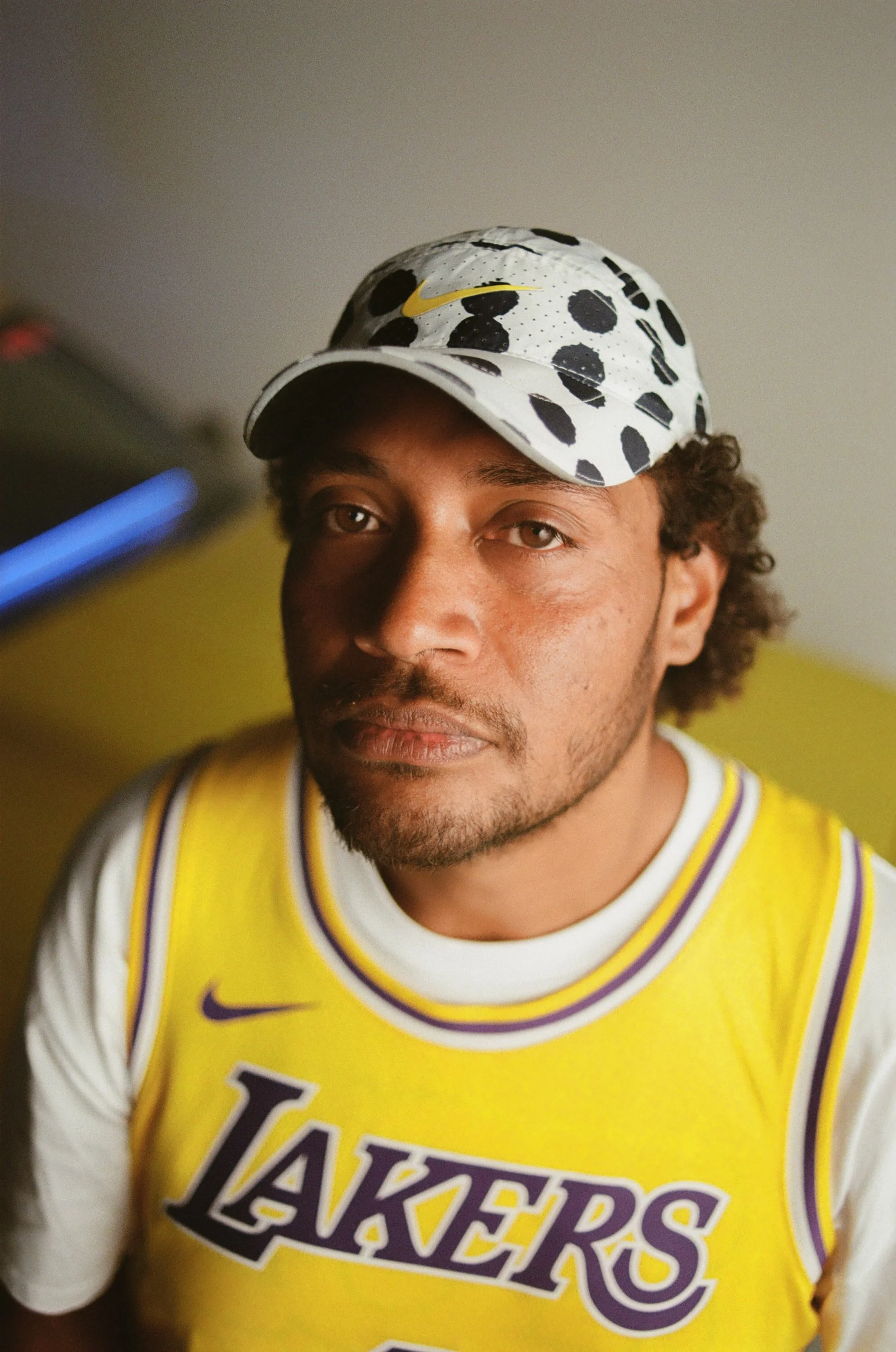 Man wearing a polka-dot cap and a yellow Lakers jersey with white and purple accents, looking into the camera.