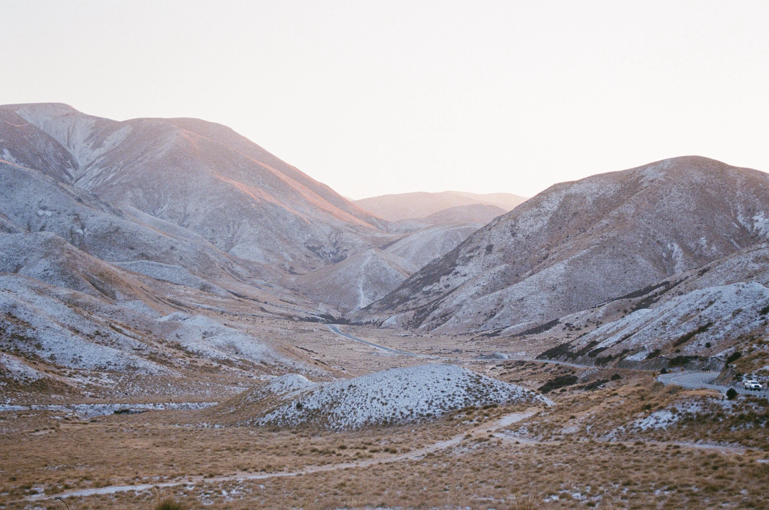 Mountain landscape with light snow cover under a cloudy sky.