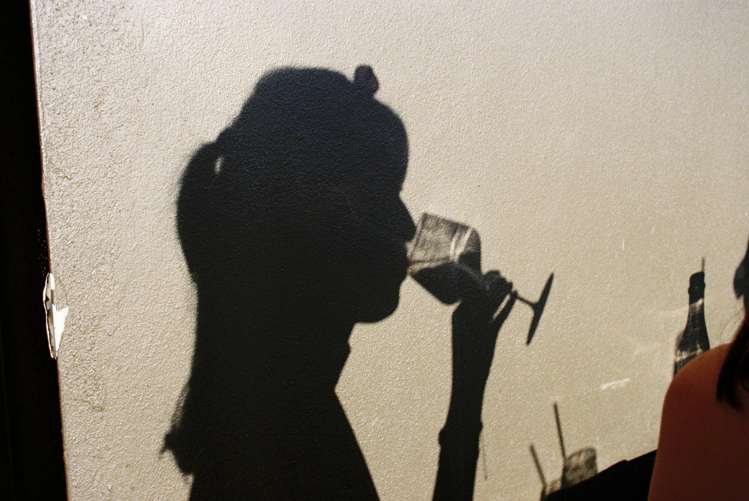 Silhouette of a person drinking from a wine glass, projected as shadow on a wall. Gold Coast restaurant marketing 