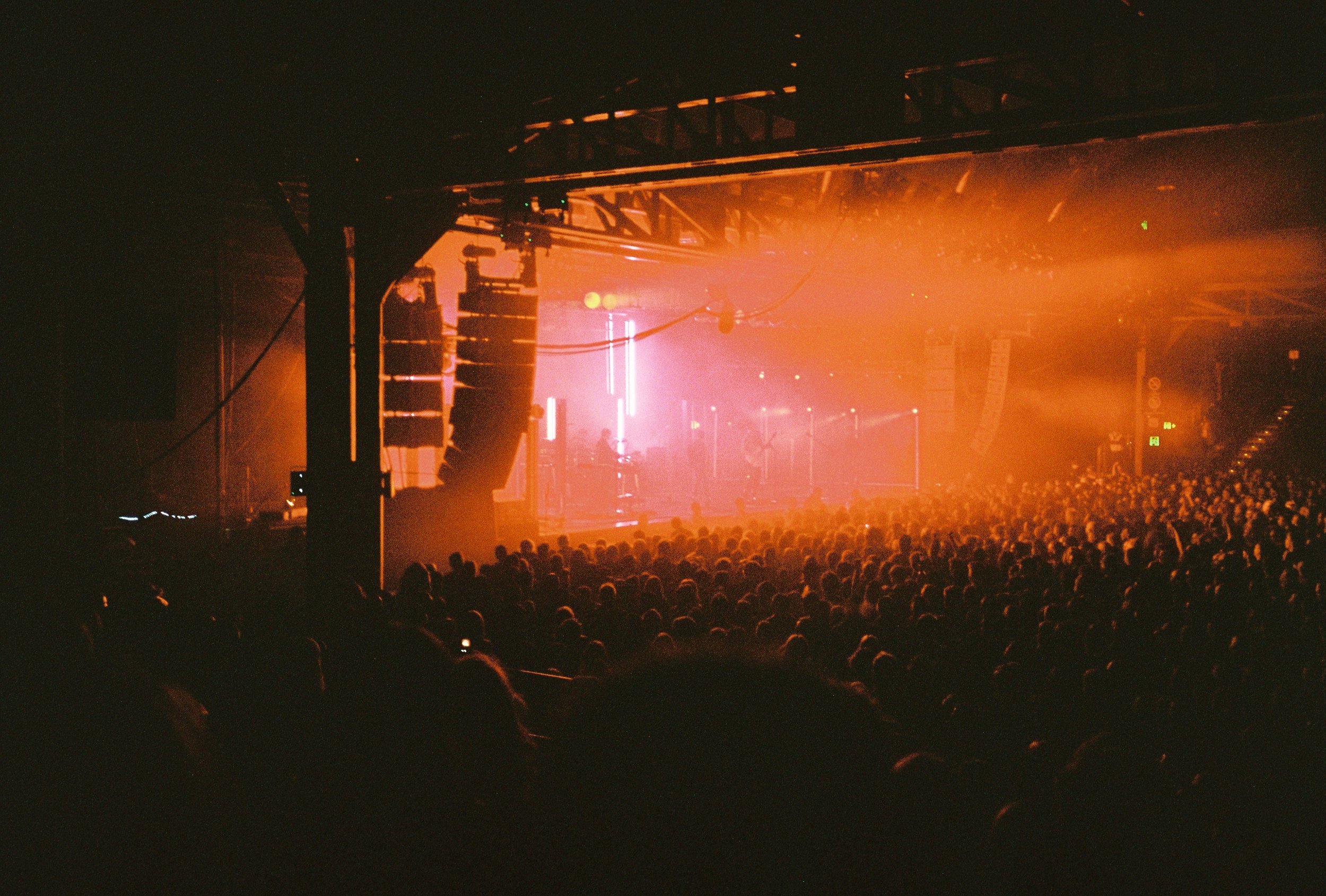 Concert with red lighting and large crowd