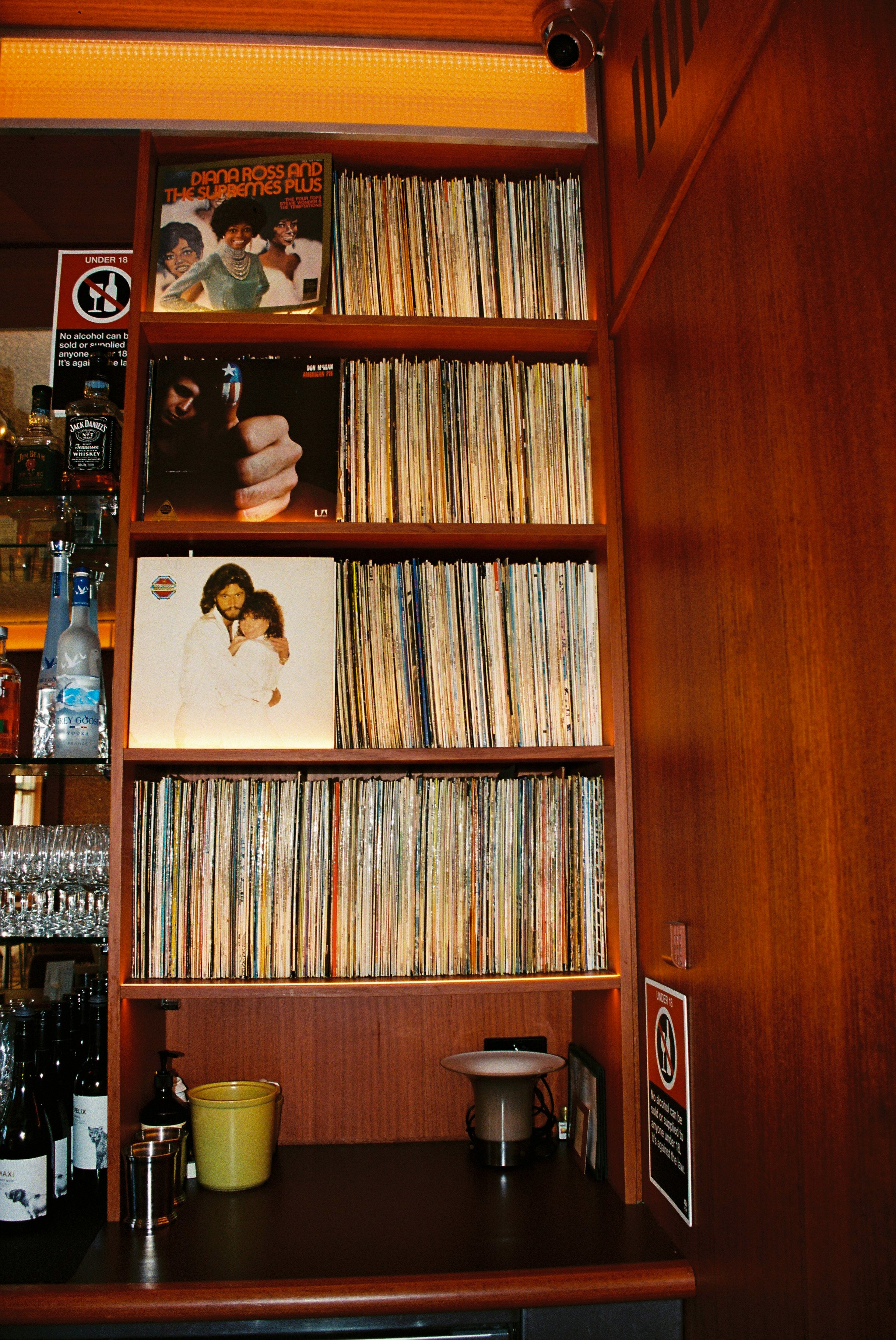 A wooden shelf filled with vinyl records, with album covers visible, including Diana Ross and the Supremes Plus, Don McLean, and Bee Gees. Sydney interior photography