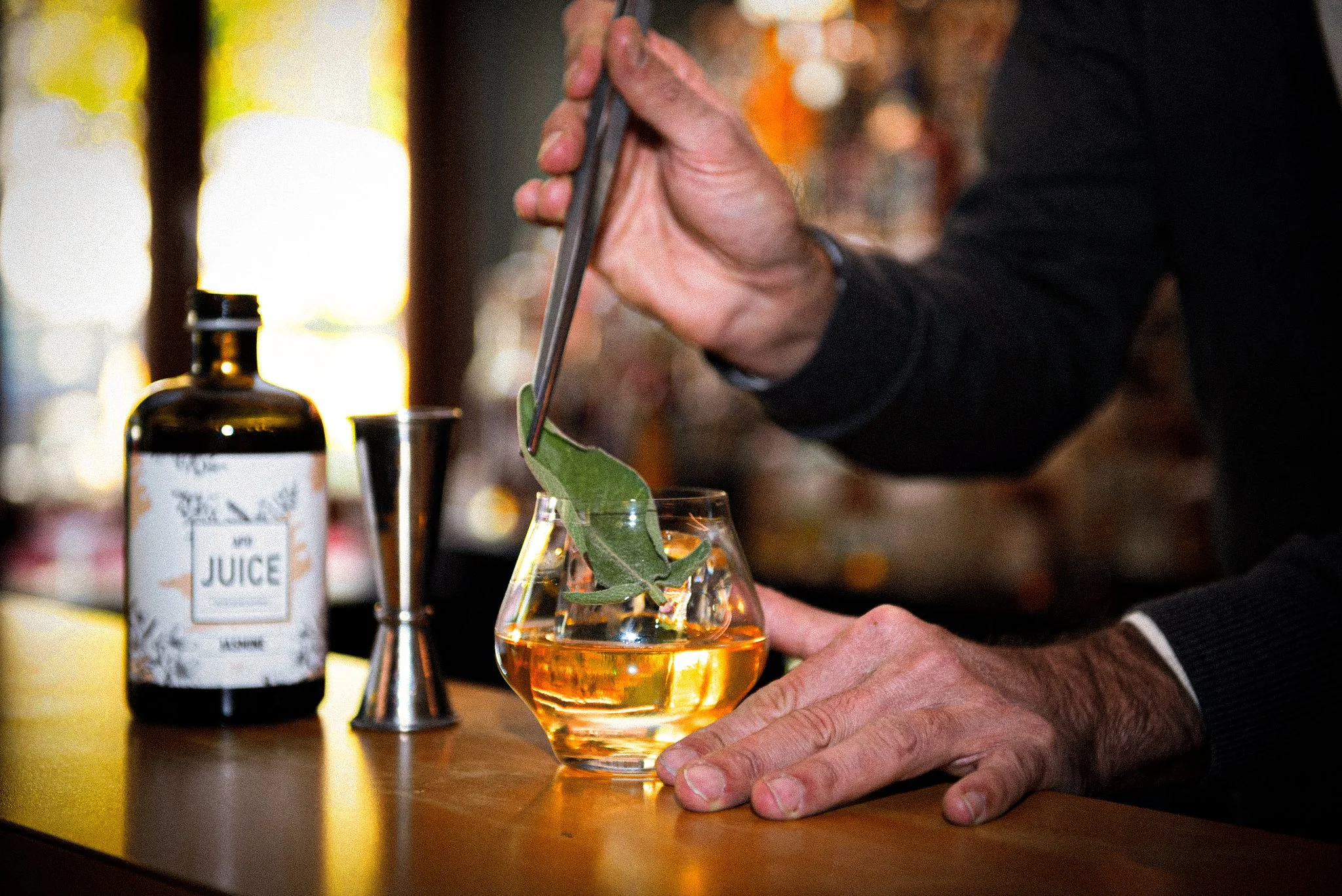 Barista che prepara un cocktail analcolico utilizzando un estratto botanico BOTANICA, guarnendo il drink con salvia durante la mixology.