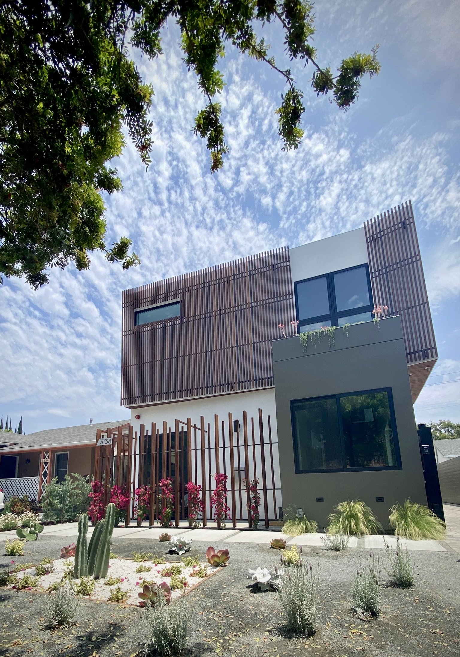 The front facade features Ipe wood screening and a green roof over the entry.