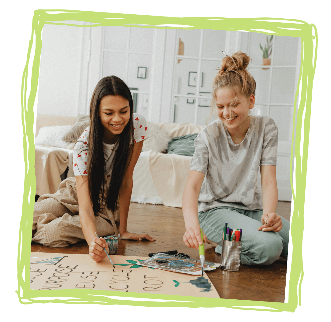 two teen girls painting a poster for girl empowerment