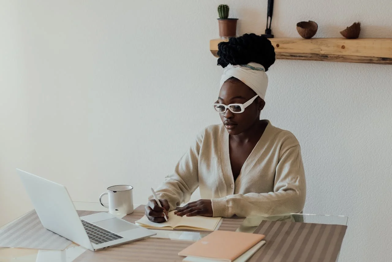 Woman with white glasses and beige sweater sitting at her computer organizing her terms of service and privacy policy for her small Ottawa business website.
