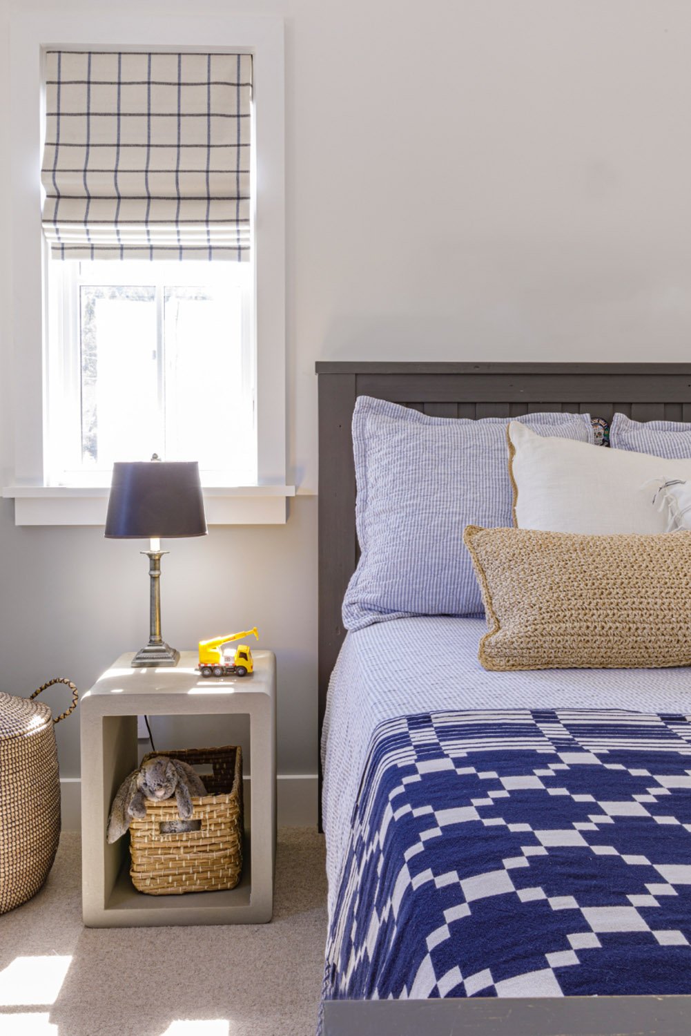 Bed with blue patterned throw and lamp on side table.jpg