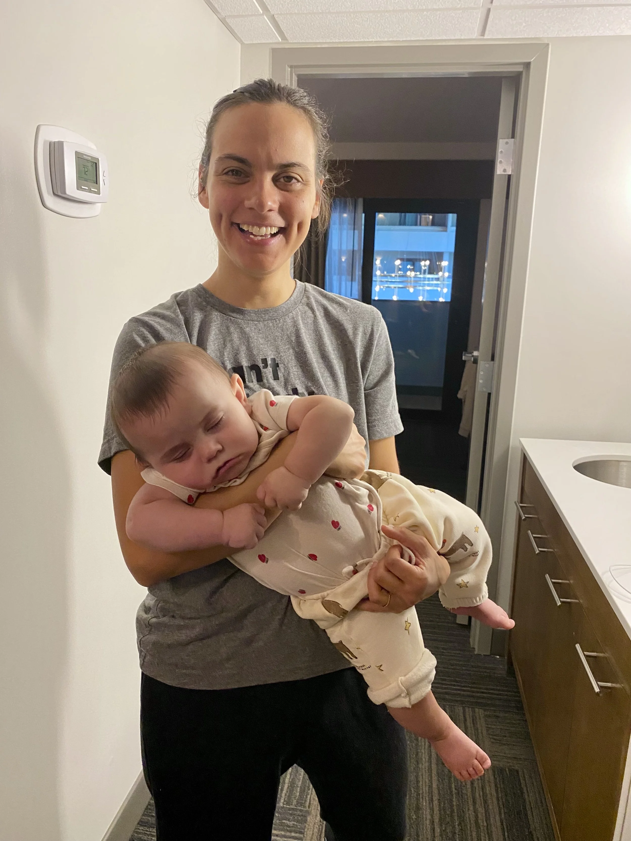 A woman who is a postpartum doula holding a baby sleeping in her arms