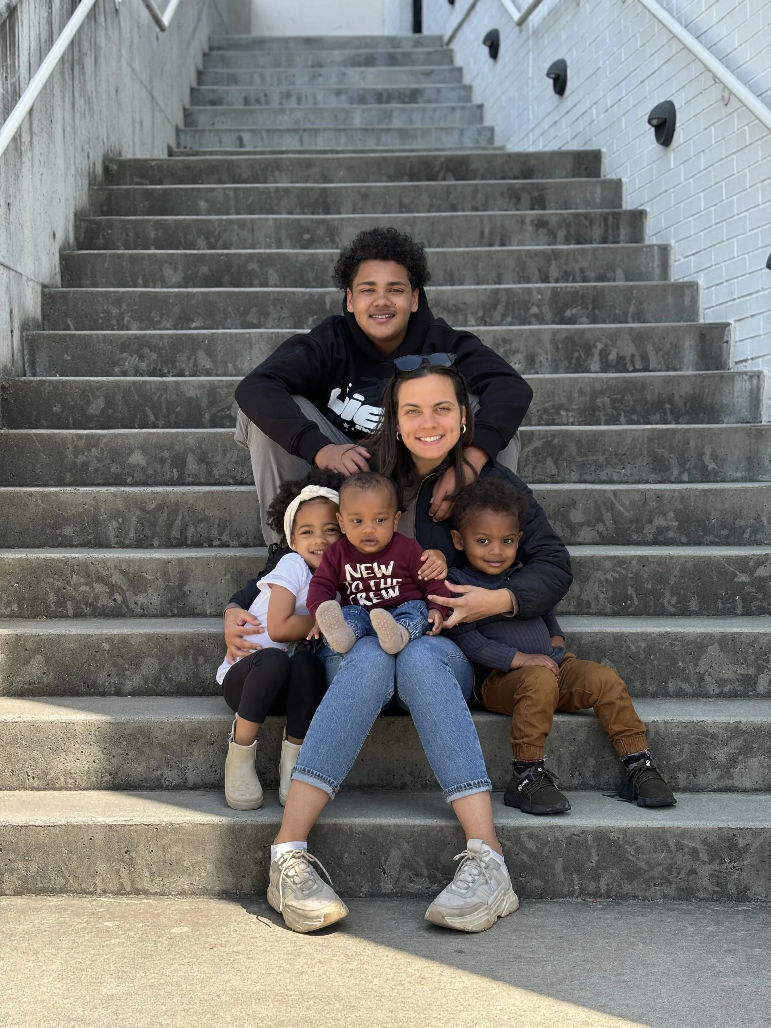 A woman sitting on staircase with her four children