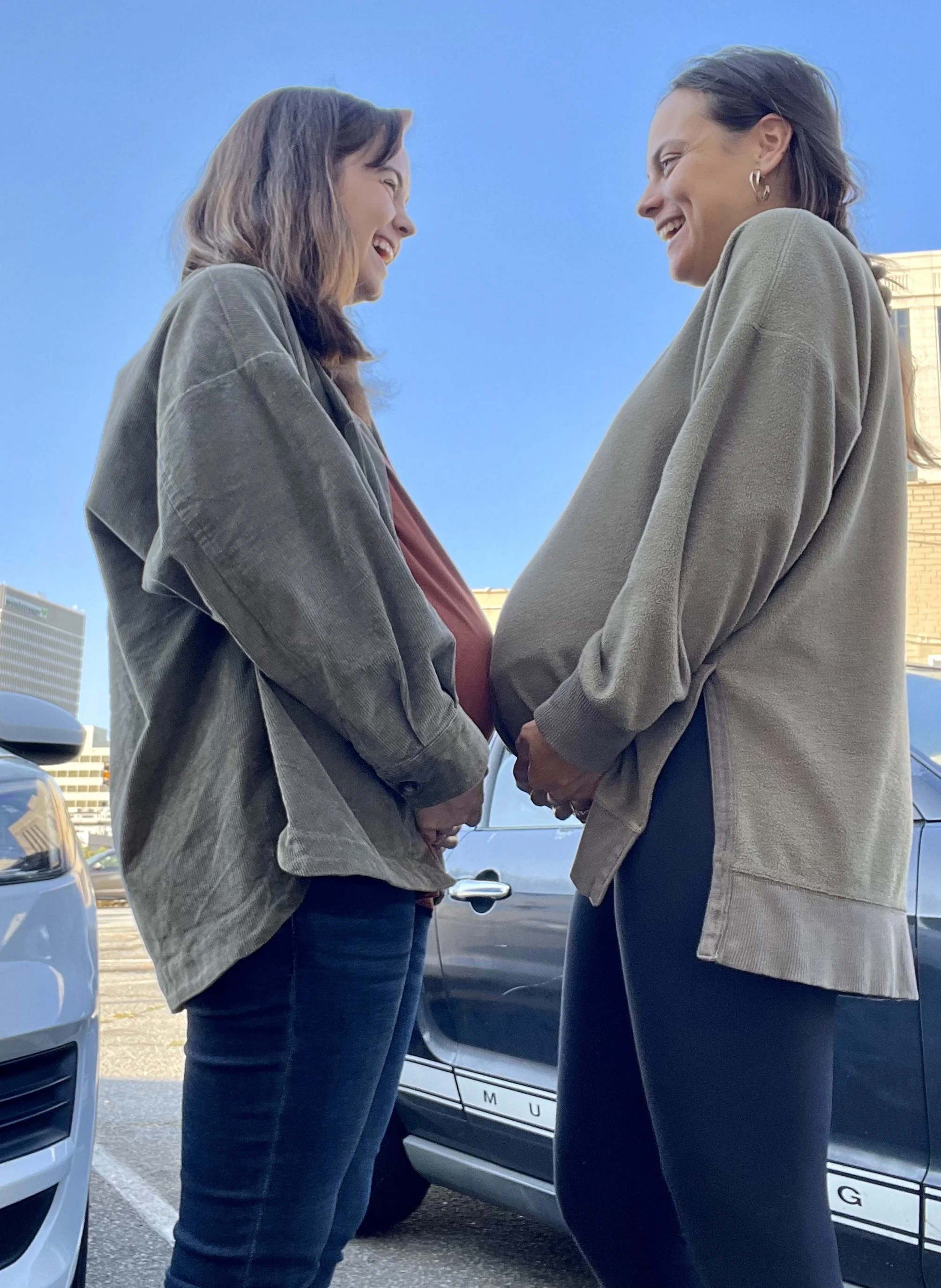 Two pregnant women standing together belly to belly
