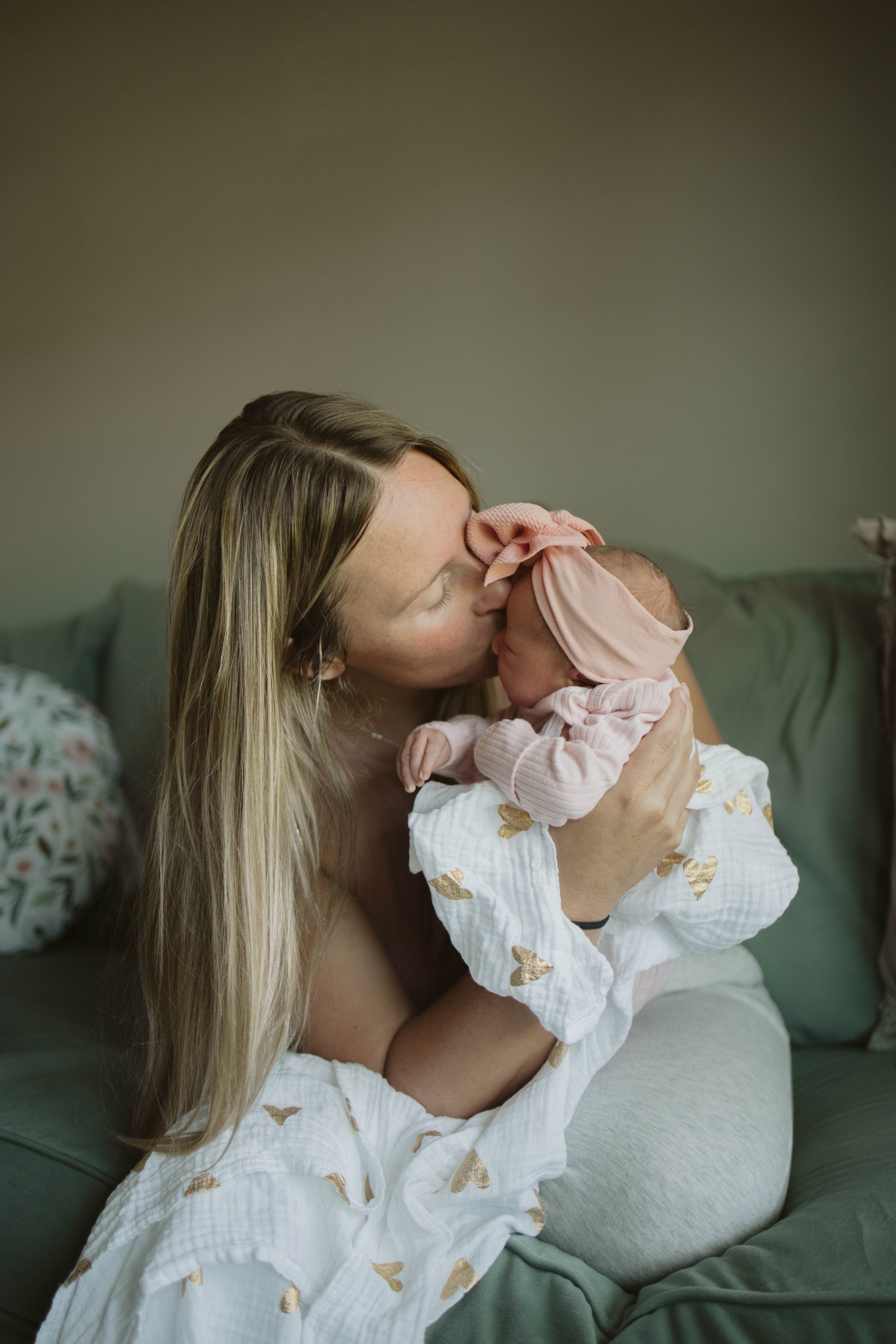 Postpartum Mom holding her baby and kissing her forehead. Mom just gave birth.