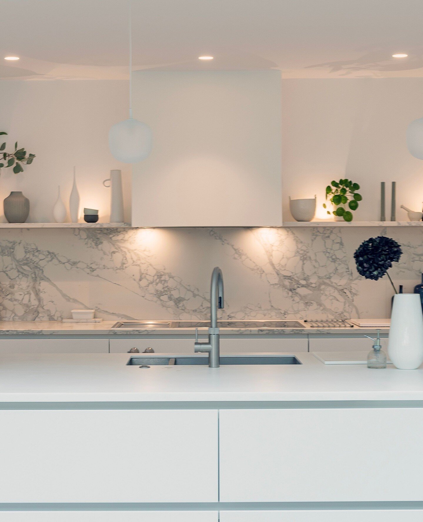This beautiful marbled quartz combined with calming white tones and soft lighting, creates a warm, serene ambience within this expansive open-plan space.⁠
⁠
Go to our link in bio to discover more photos of this stylish kitchen. ⁠
⁠
Designer: @ashley_