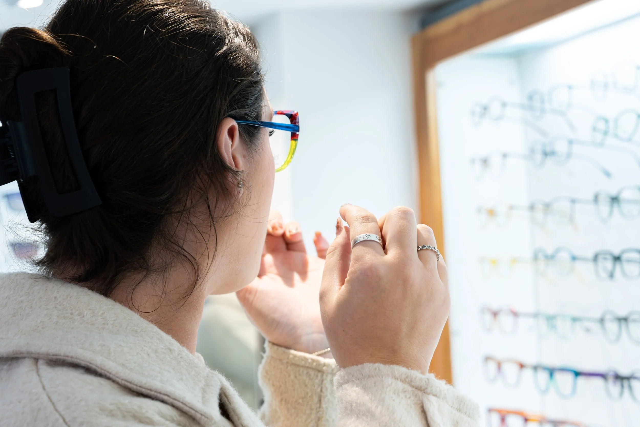 Woman trying on glasses at an eyewear shop.