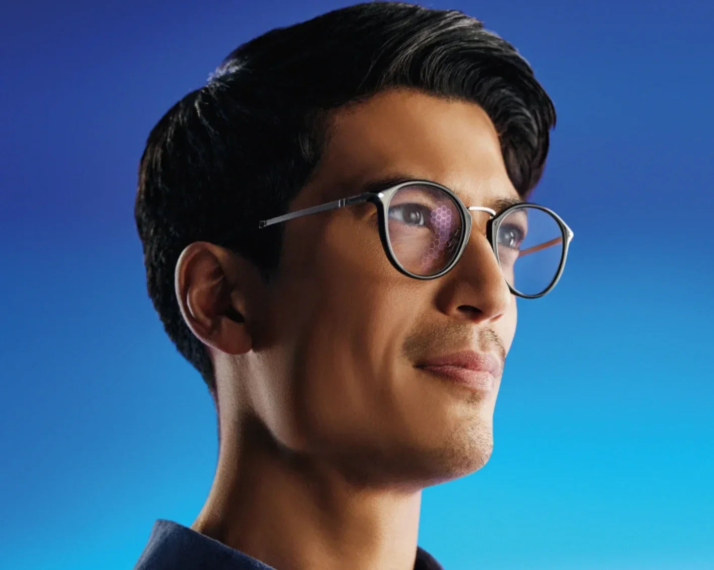 A man with short dark hair and glasses looks upwards, set against a blue gradient background—Varifocal lenses explained.