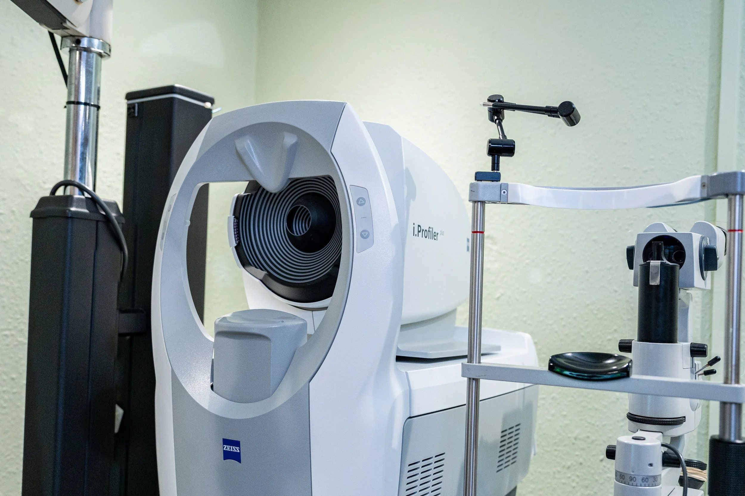 Medical equipment in a clinical setting, including an i.Profiler for eye testing and a slit lamp microscope.