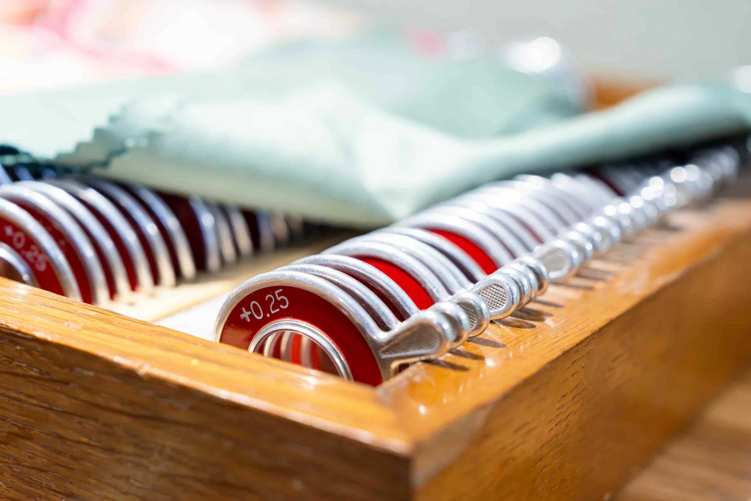 A set of red and silver poker chips in a wooden rack, labeled with +0.25, with some paper money in the background.
