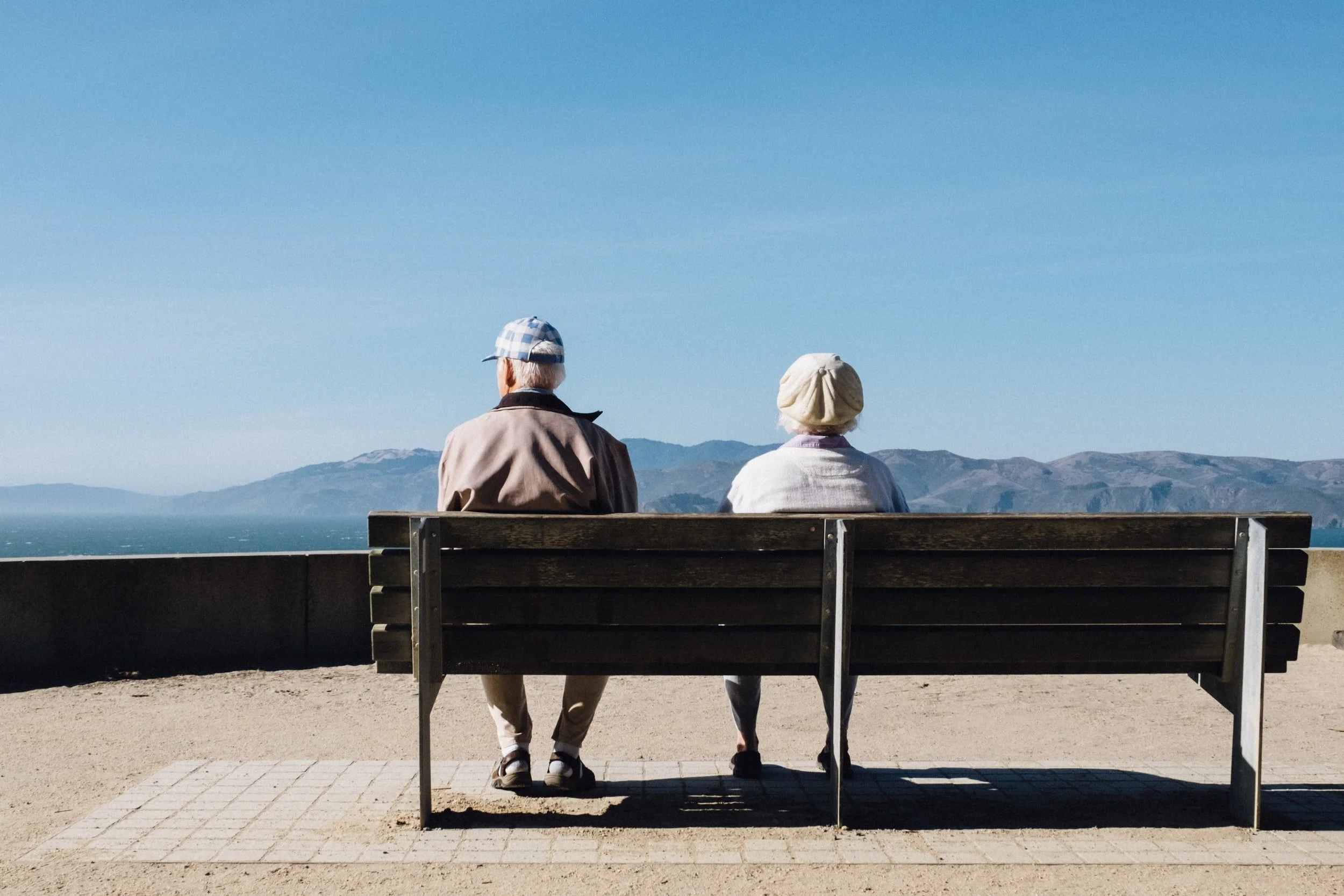 Healthy aging couple sitting on a park bench representing longevity, vitality, and enjoying life during the healthspan years