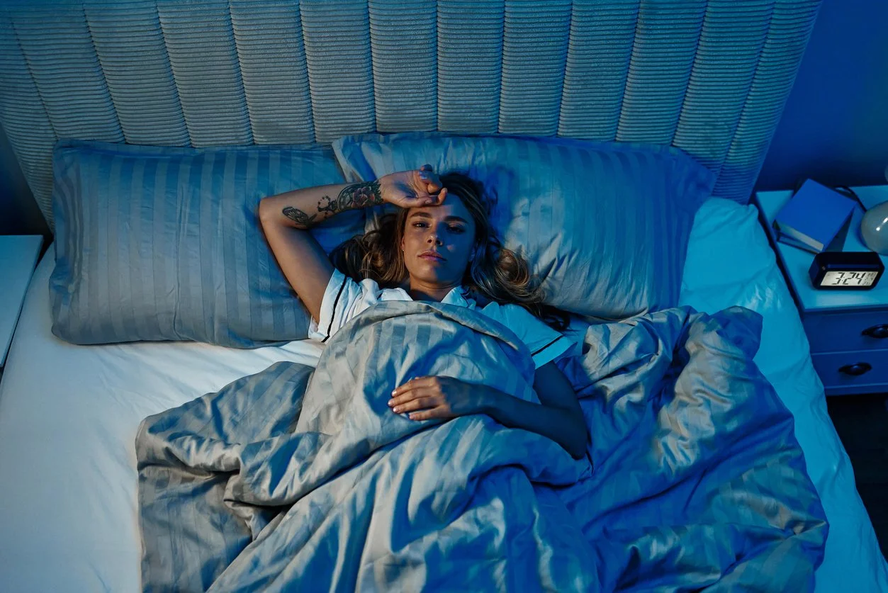 Tired person lying awake in bed at night, struggling with insomnia and waking up around 2 or 3 AM – common sleep disorder symptoms addressed with functional medicine
