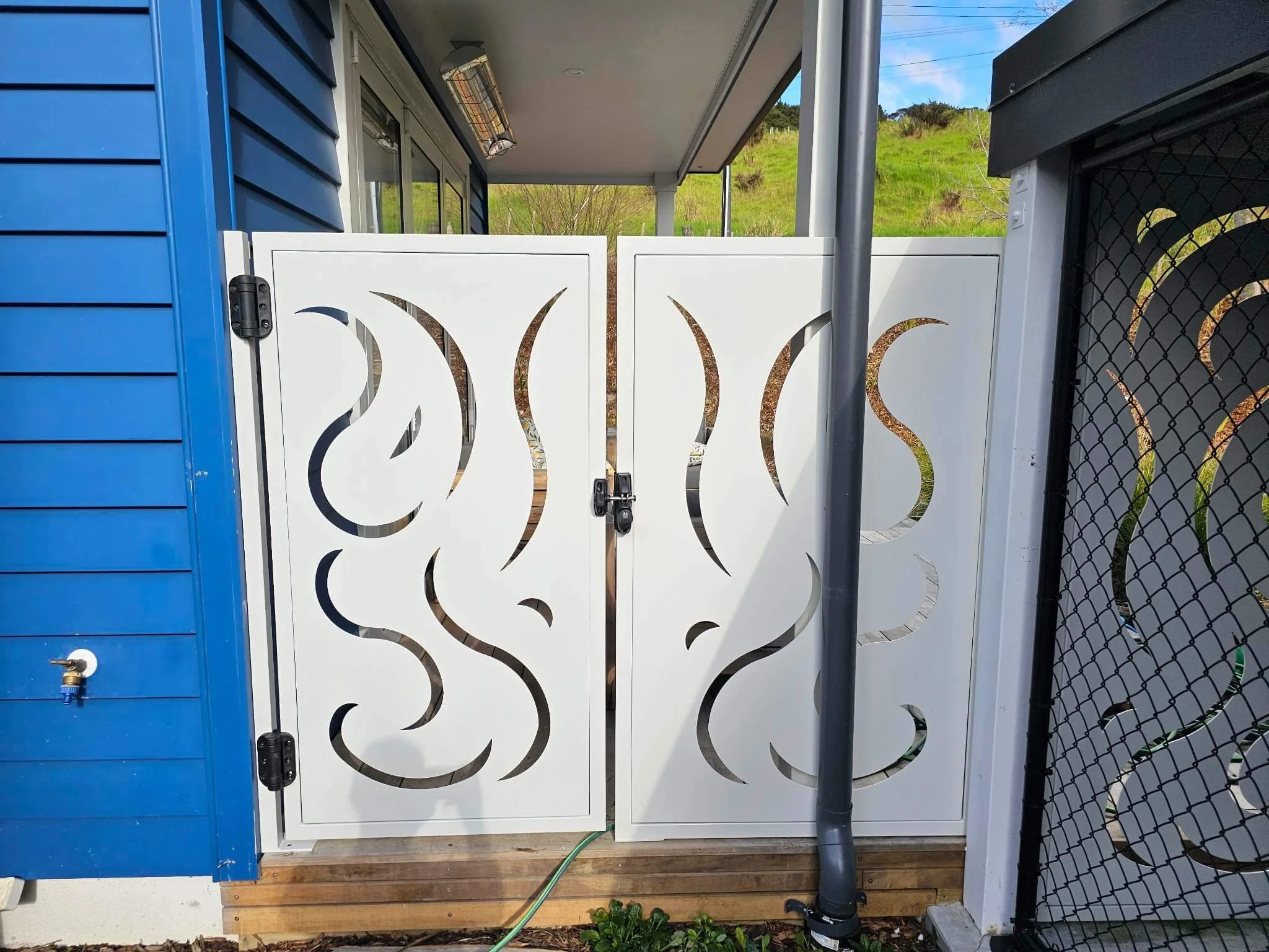white bespoke steel gate with curvy designs cut into the steel